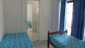 Een kamer met twee bedden, een deur naar een andere kamer en een raam met gordijnen.