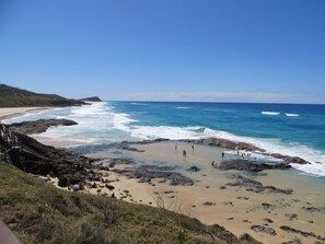 A beach with rocky areas and waves crashing onto the shore.