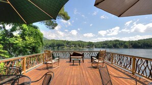 A wooden deck with outdoor seating and a view of a lake.