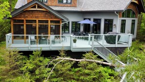 A two-story house with a covered deck and a staircase leading to a second level.