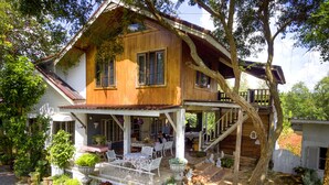 A two-story wooden house with a covered porch and a staircase leading to the upper floor. - Rosemary House (Pak Chong)