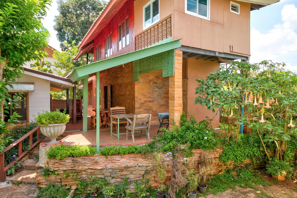 A house with a covered patio, stone wall, and potted plants.
