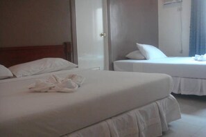 A hotel room with two beds, a wooden headboard, and a white bathroom. - Balibago Villa Hotel (Angeles City)