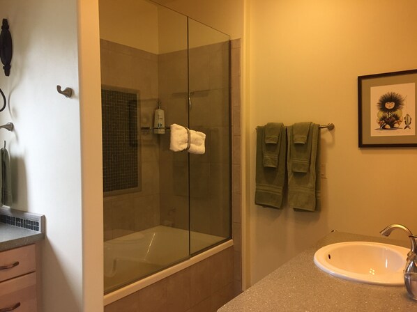 Une salle de bain avec une douche à parois de verre, un lavabo et des serviettes rangées sur un porte-serviettes.