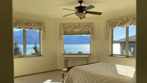 Un dormitorio con cama, ventilador de techo y ventanas amplias con vistas a la montaña.