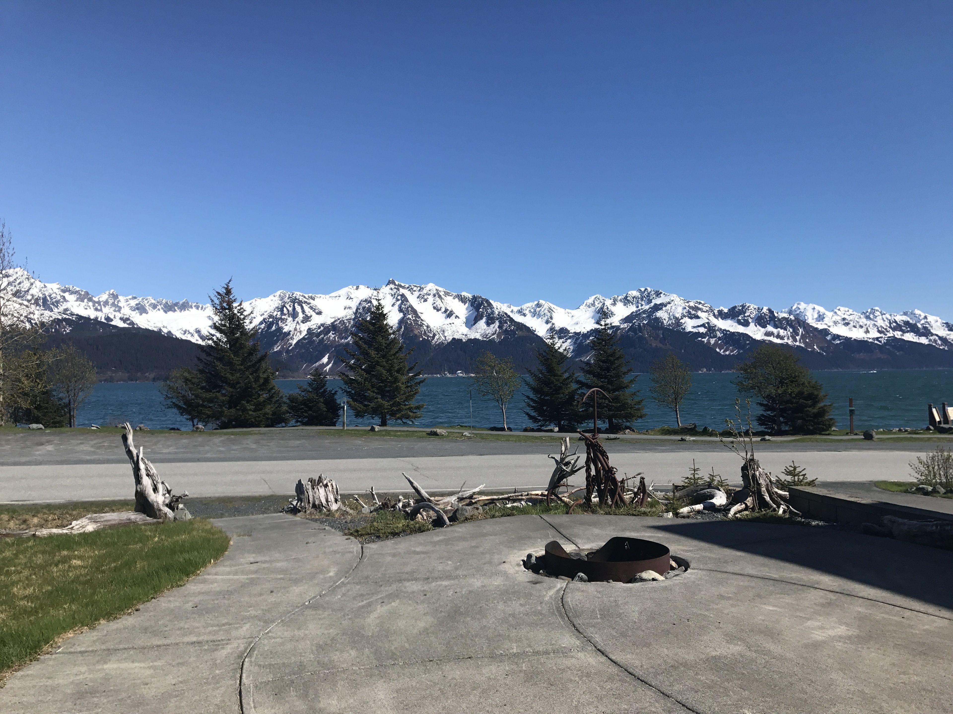 A parking area with a view of snow-capped mountains and a lake.