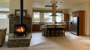 Una cocina amplia con chimenea de piedra, armarios de madera y una isla grande con taburetes de bar.