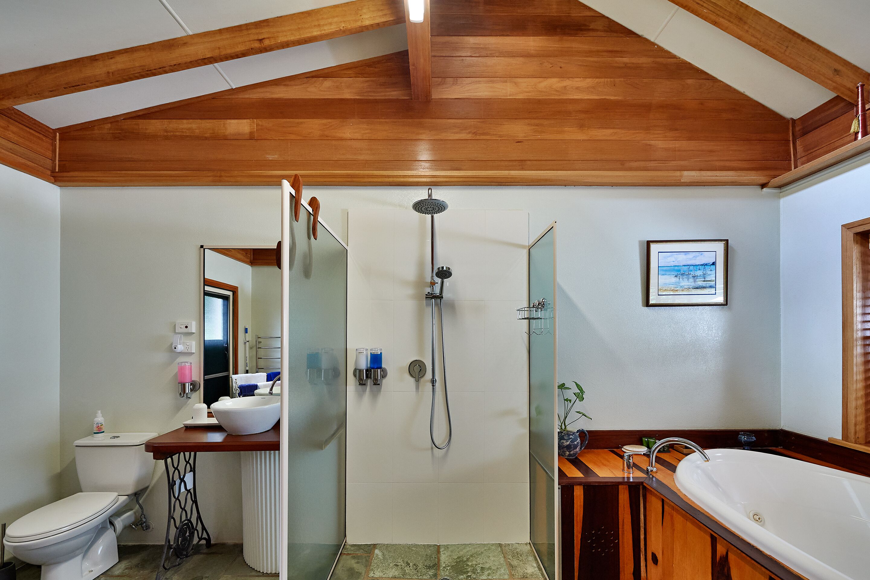 A bathroom with a wooden ceiling, a shower, a toilet, a sink, and a bathtub.