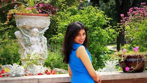 A woman in a blue dress standing next to a brick wall with a garden. - A Sweet Suite in a Stunning Chalet-style Home -- YYZ (Toronto)