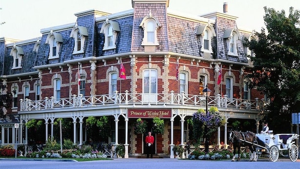 A historic hotel with a prominent entrance, a balcony, and a horse-drawn carriage. - A Sweet Suite in a Stunning Chalet-style Home -- YYZ (Toronto)