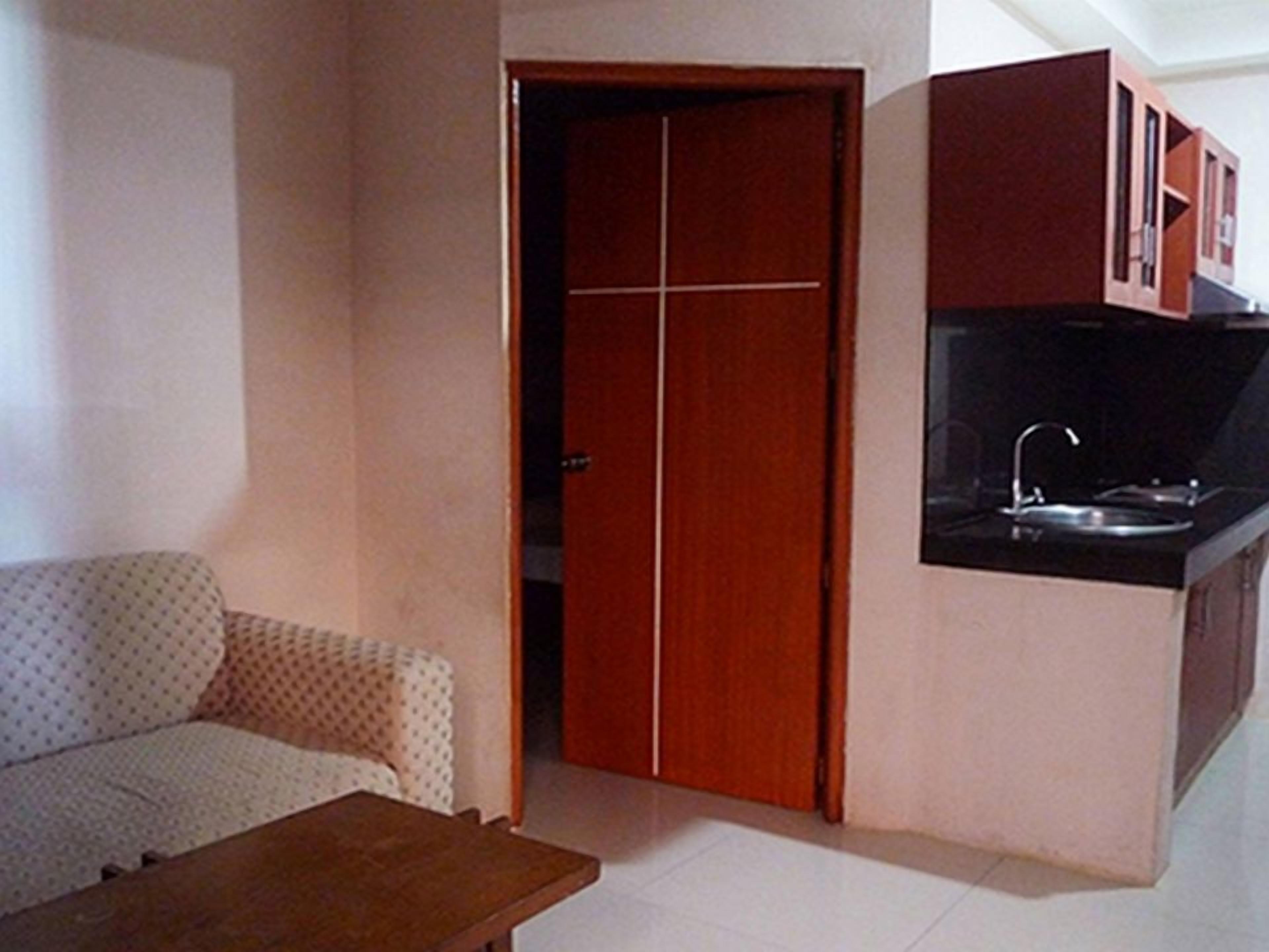 A compact living space with a kitchenette, a sofa, and a wooden table.