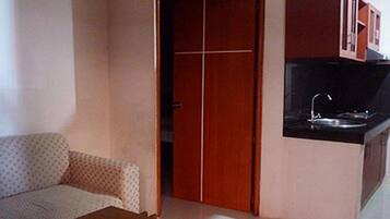 A compact living space with a kitchenette, a sofa, and a wooden table.
