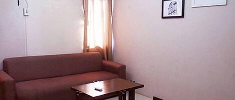 A living room with a sofa, a small wooden table, and a wall-mounted air conditioner.