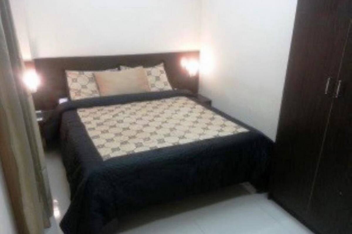 Un dormitorio pequeño y ordenado con cama, mesitas de noche y un armario.