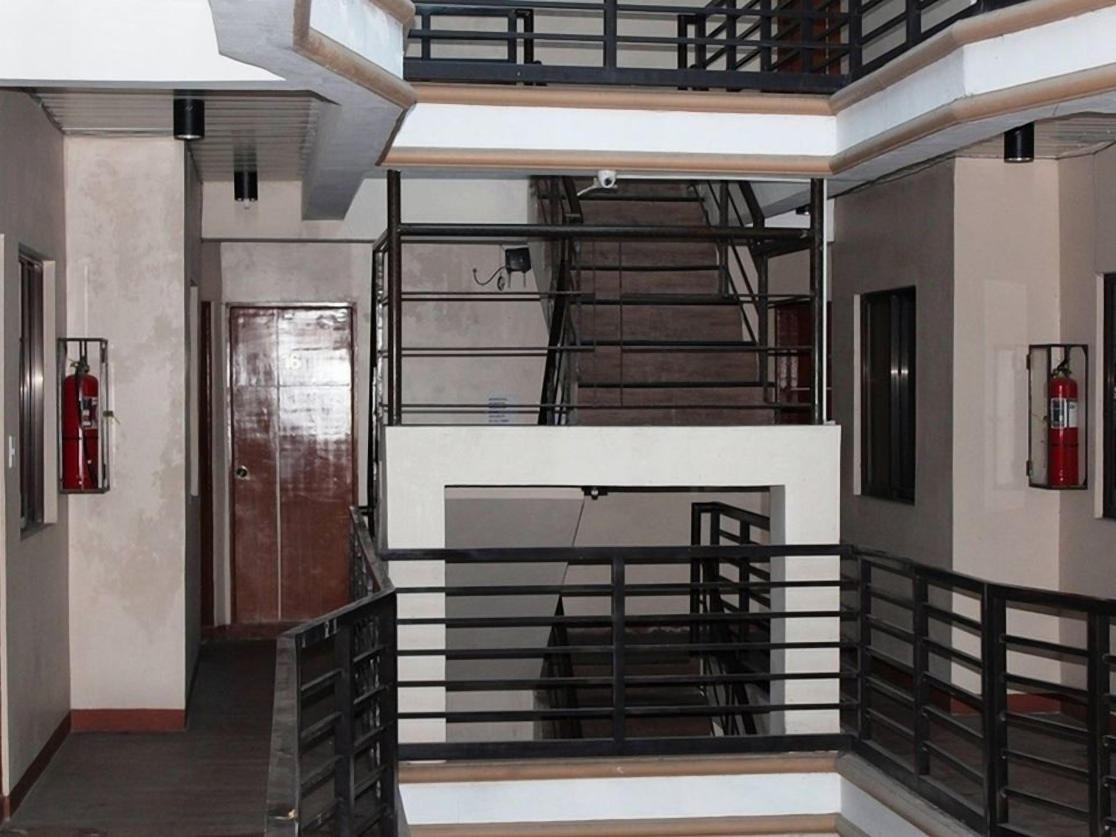 Ein mehrstöckiger Innenraum mit Treppe, Feuerlöscher und einer Tür.