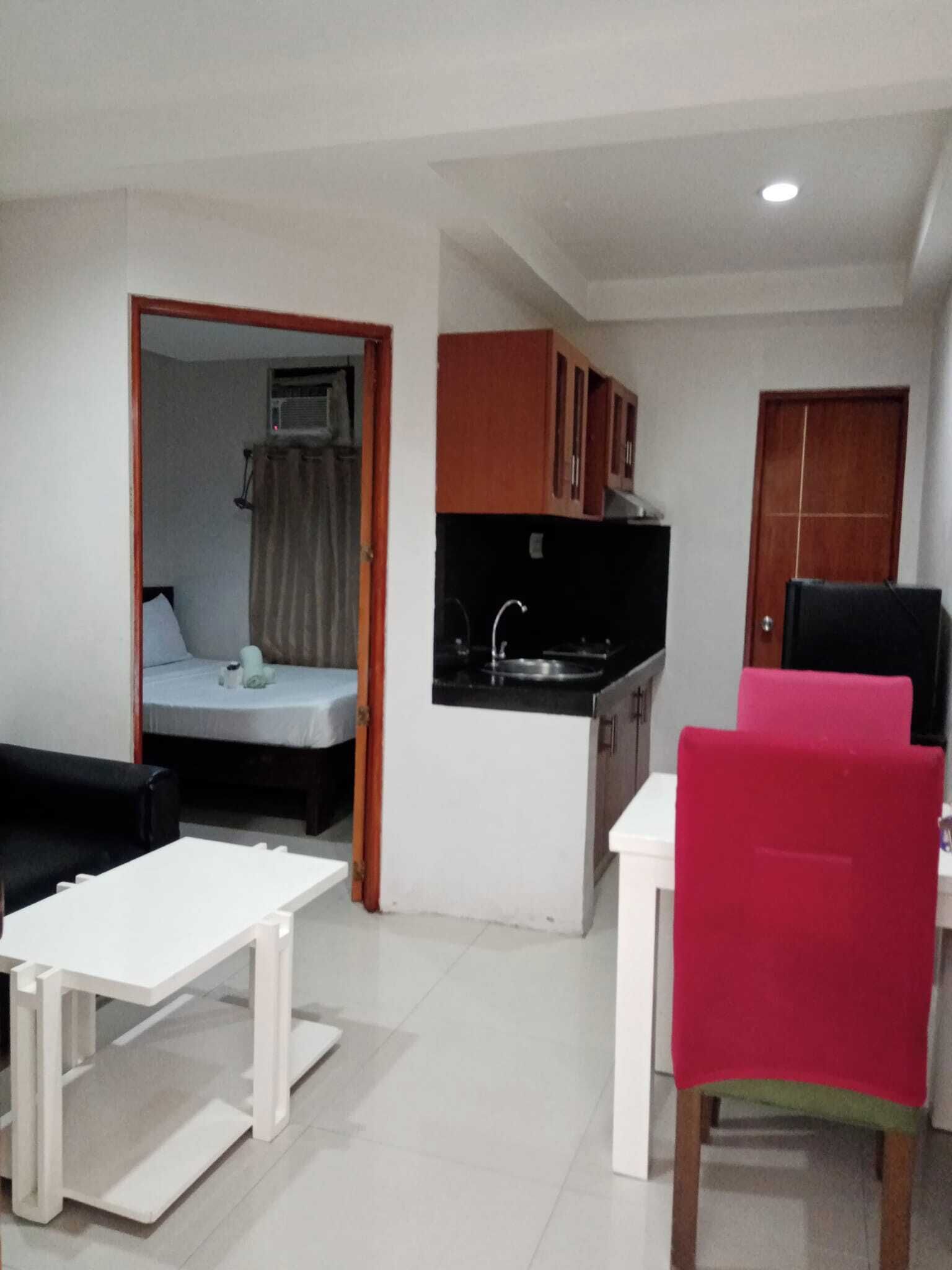 A compact living space with a kitchenette, a dining area, and a small bedroom.