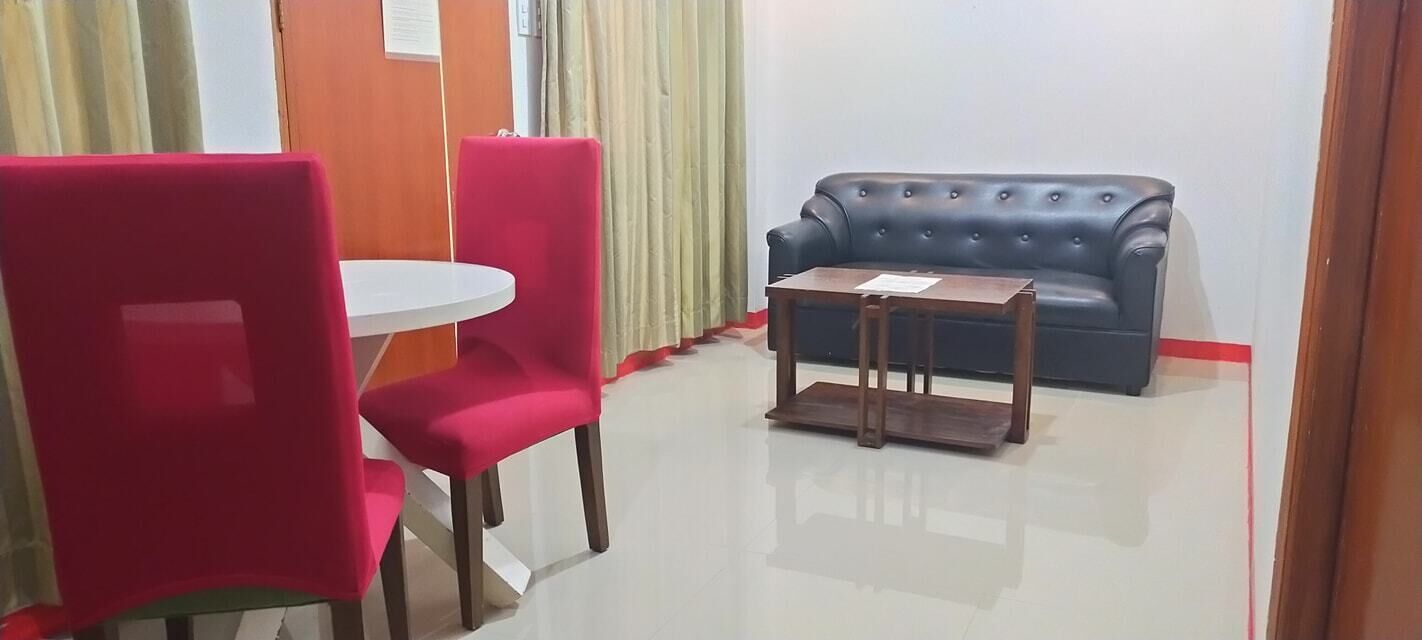 A room with a blue sofa, a small wooden table, and two red chairs.
