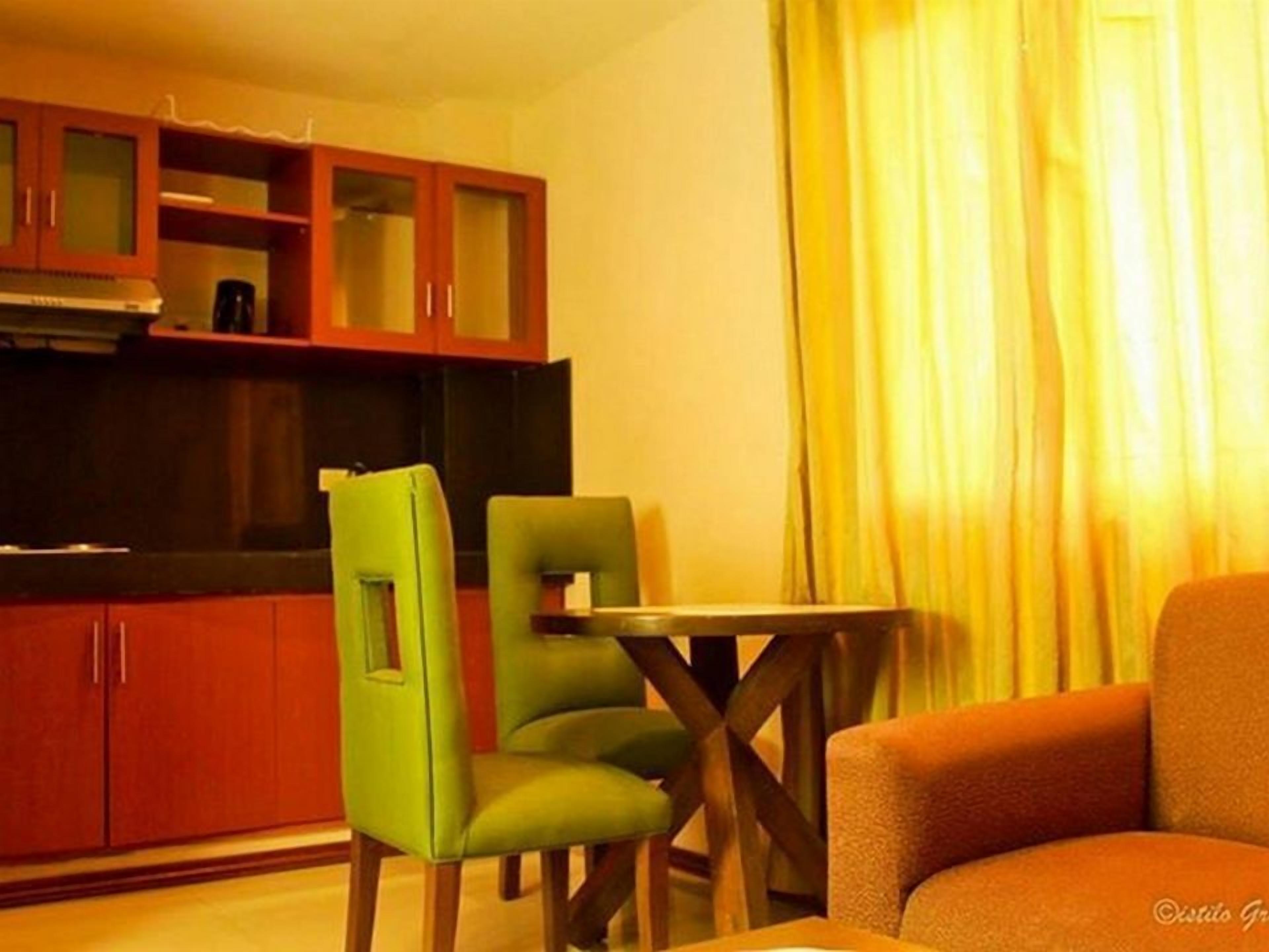 Un espacio habitable compacto con kitchenette, un comedor con dos sillas y un sofá.