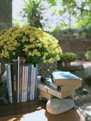 A bookshelf with books and a yellow flower arrangement. - Confetti House (Quy Nhon)