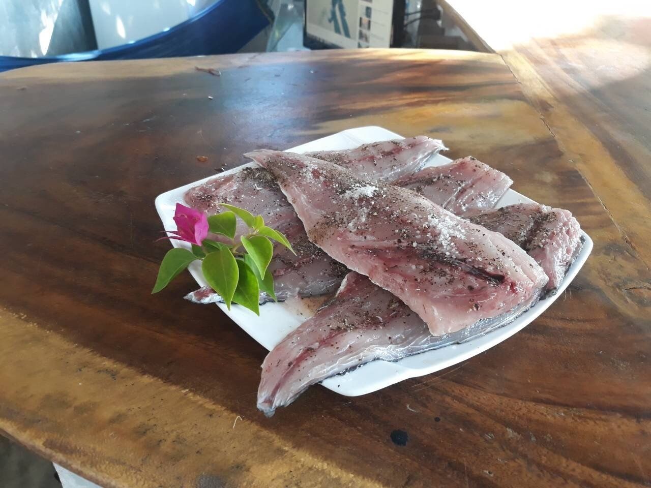 Ein Teller mit rohem Fisch auf einer Holztischplatte.