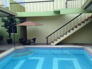 Ein Pool mit Stufen, einer Treppe und einem Tisch mit Stühlen unter einem Sonnenschirm.