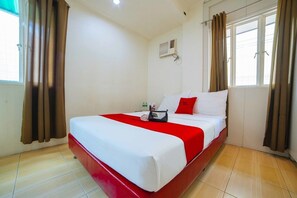 Ein Hotelzimmer mit einem Einzelbett, einem fenster mit Vorhängen, einer Wand-Klimaanlage und einem Fliesenboden.