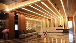 A modern lobby with a curved ceiling, a reception desk, a sofa, and a glass coffee table. - Hotel Château Anping (Tainan)