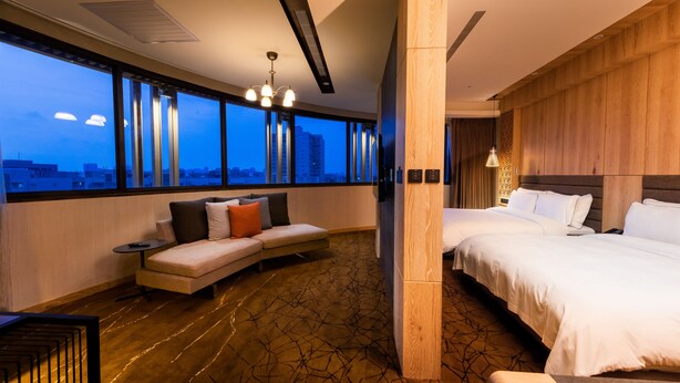 A modern hotel room with a large window, a sofa, a bed, and a small table. - Hotel Château Anping (Tainan)