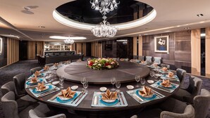 A round dining table with a floral centerpiece, surrounded by upholstered chairs with gold bead trim. - Hotel Château Anping (Tainan)