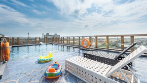 A rooftop pool with inflatable toys, lounge chairs, and a city view. - Hotel Château Anping (Tainan)