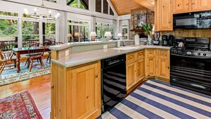 Una cocina amplia con armarios de madera, una isla grande y vistas al exterior a través de ventanas grandes.