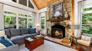 Una sala de estar acogedora con chimenea de piedra, ventanas amplias y asientos cómodos.