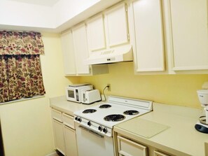 A compact kitchen with a white stove, microwave, and toaster.