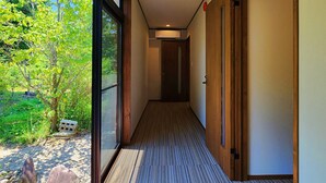 A hallway with a view of greenery outside, a carpeted floor, and wooden doors. - Tourist MINOWA (Ueda)