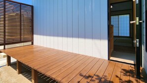 A wooden deck with a bench, a sliding door, and a white exterior wall. - Tourist MINOWA (Ueda)