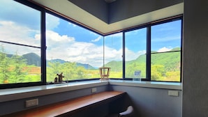 A corner office with a desk and two chairs, large windows with a view of green hills and a clear sky. - Tourist MINOWA (Ueda)
