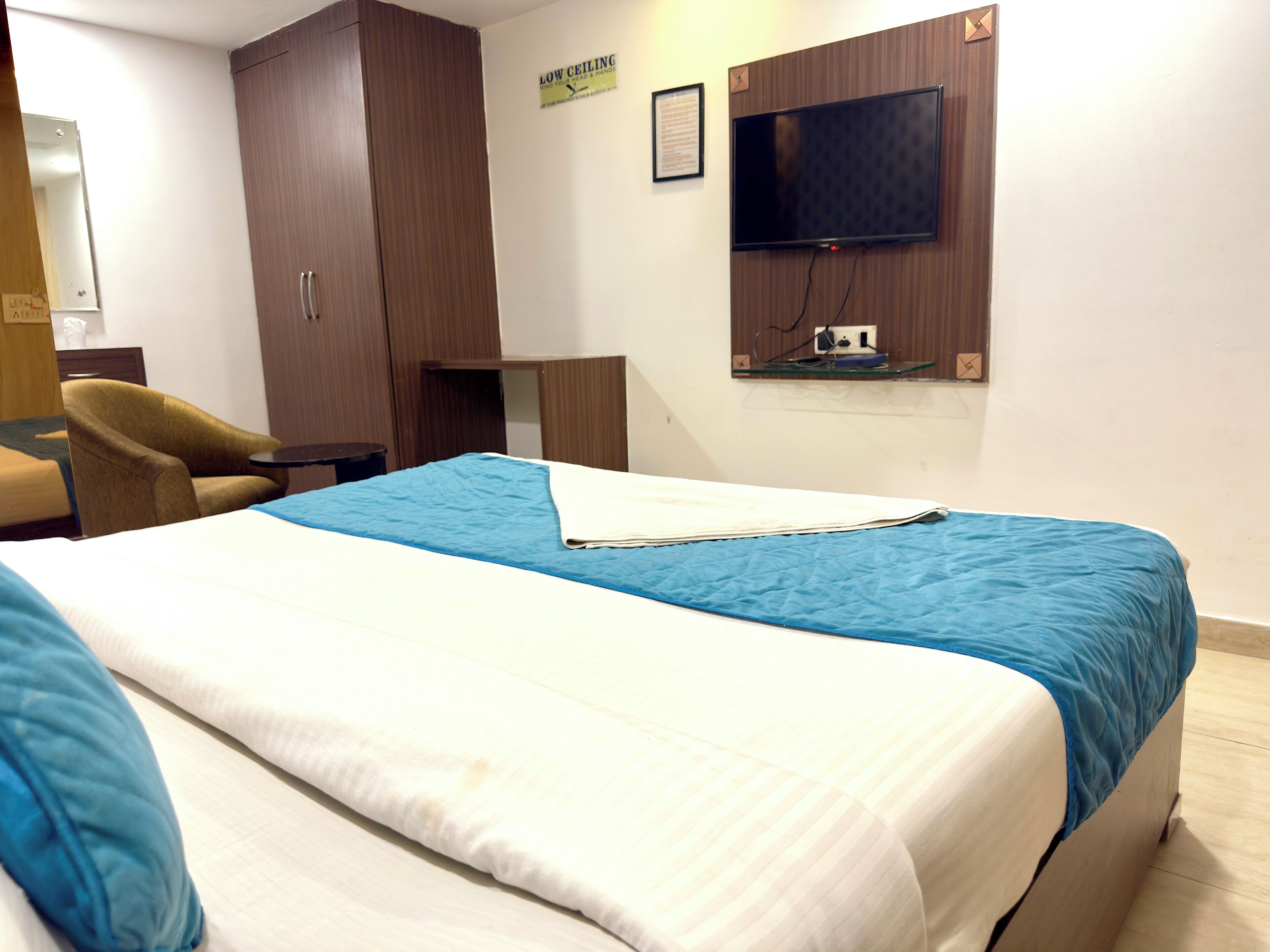 A hotel room with a bed, a chair, a wardrobe, a television, and a small table.