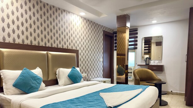 A hotel room with a large bed, a desk, and a chair. - Hotel Pawan Plaza - Near BLK and Ganga Ram Hospital - Karol Bagh (New Delhi)