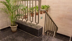 A marble staircase with metal railings, potted plants, and an exit sign. - Hotel Pawan Plaza - Near BLK and Ganga Ram Hospital - Karol Bagh (New Delhi)