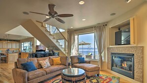 A spacious living room with a fireplace, a sofa set, a coffee table, and a staircase leading to an upper level. - 'Casa d'Amore': Extravagant Lakefront Villa! (Granite Bay)