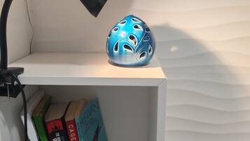 Ein weißes Regal mit einem blauen Keramikobjekt und Büchern.