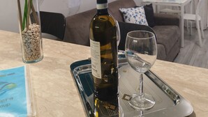 Ein Essbereich mit einem Tisch für zwei Personen, einschließlich einer Weinflasche und einem Glas. Außerdem ist eine Vase mit bunten Tulpen und ein Tablett mit einem Buch sowie einem Glas zu sehen.