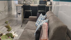 Eine moderne Küche mit Kochinsel, Pendelleuchten und einem Essbereich mit einer Couch und Stühlen.