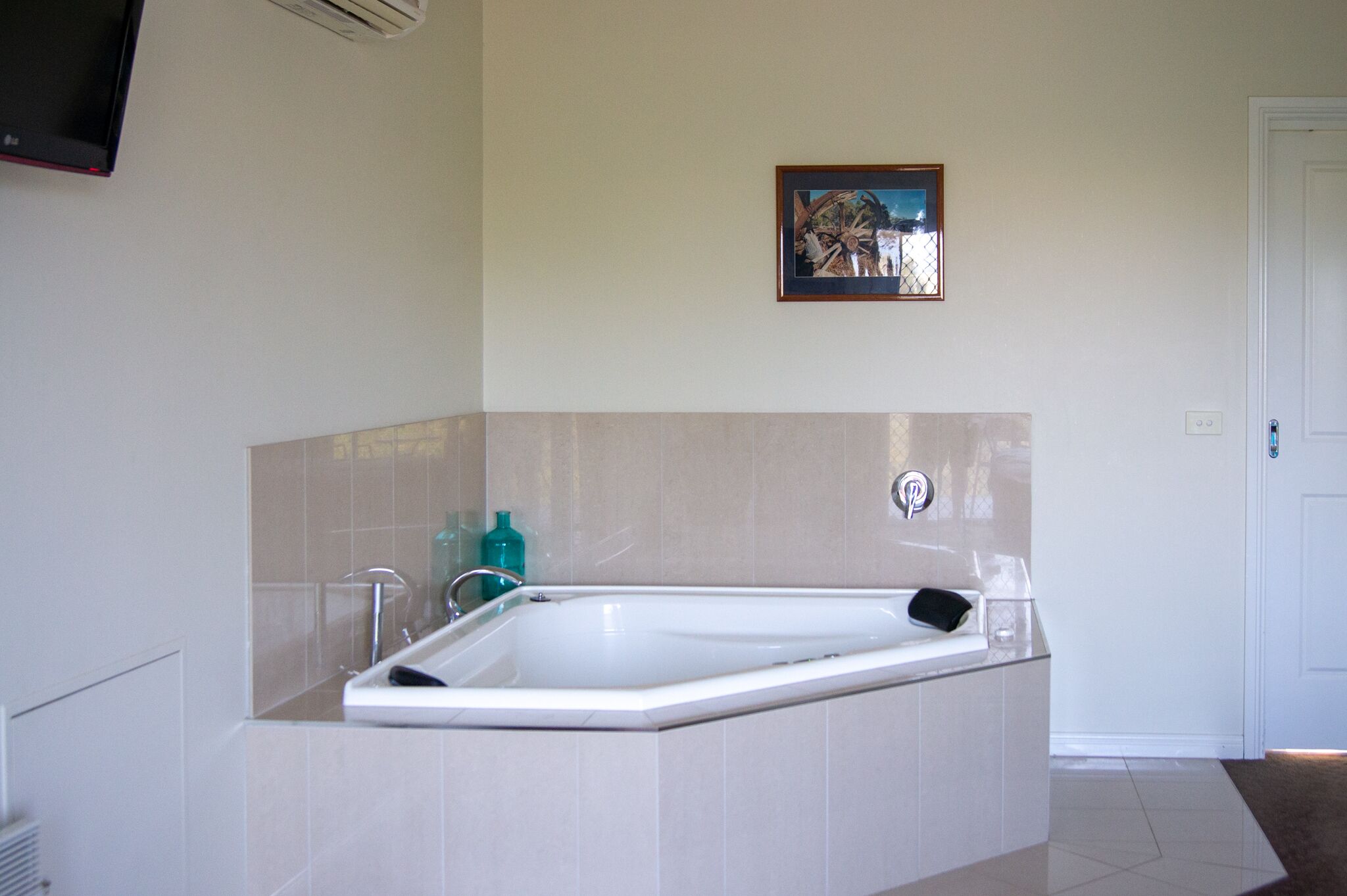 Un bagno moderno con una vasca freestanding, un televisore a parete e un quadro incorniciato sopra la vasca.