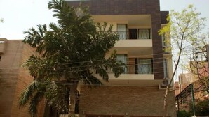 A multi-story residential building with a flat roof, balconies, and a brick facade. - East End Retreat (New Delhi)