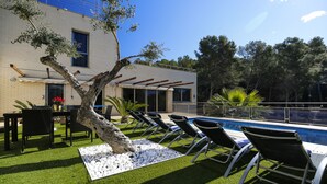 Un espace aménagé au bord de la piscine, avec des chaises longues, une petite table et une plante en pot.