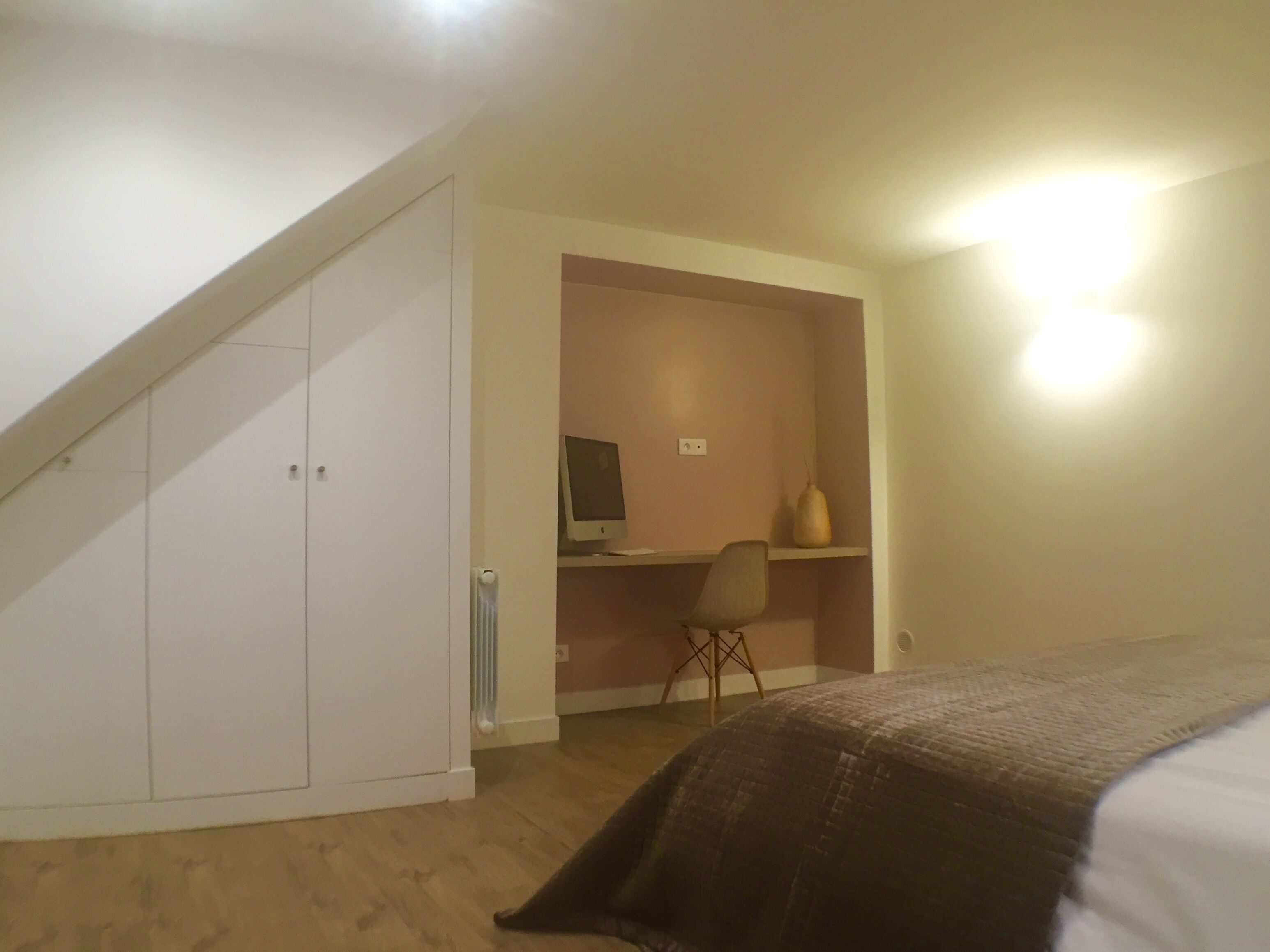 A bedroom with a bed, a desk with a computer, and a chair.