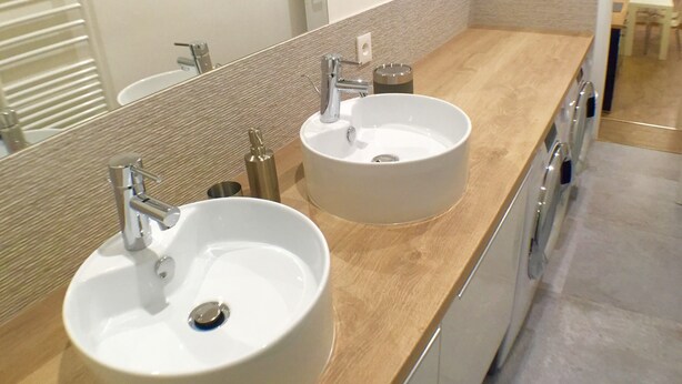 Un baño moderno con dos lavamanos, un espejo y una encimera de madera.