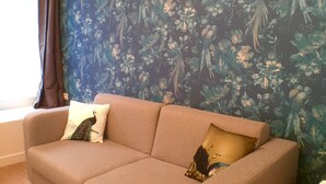 Una sala de estar con un sofá, una mesita redonda y una pared con estampado floral.