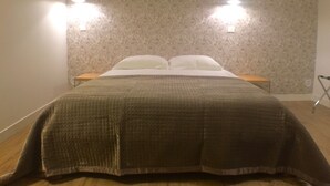 Una cama bien tendida con un edredón acolchado, dos mesitas de noche y un papel tapiz estampado.
